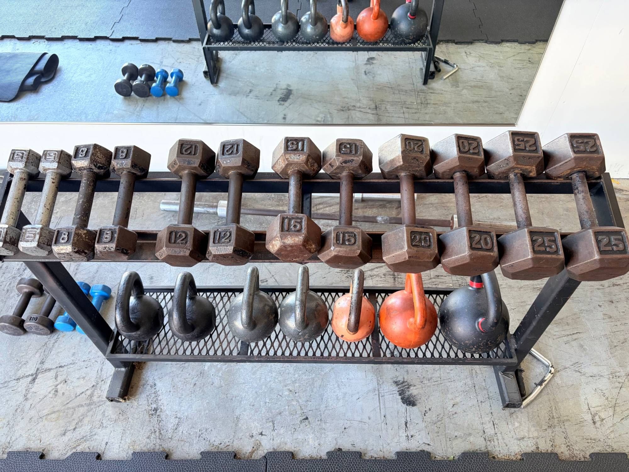 Hex dumbbells from 5 to 25 pounds with kettlebells racked underneath